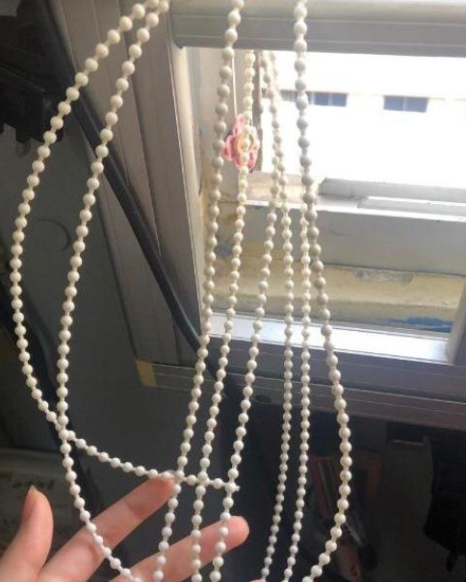 Tangled white bead chain on a roller blind