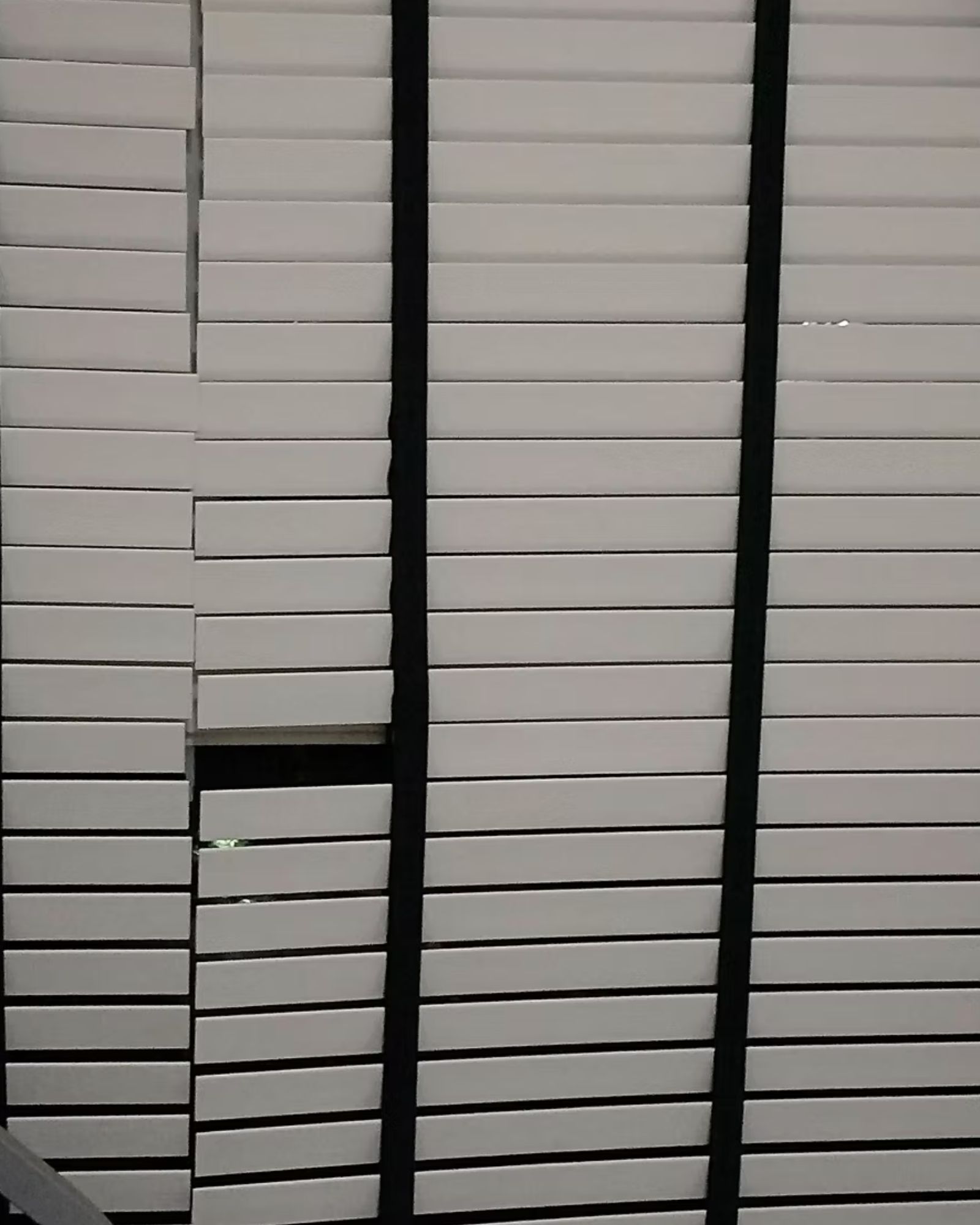 White venetian blind with a dislodged slat